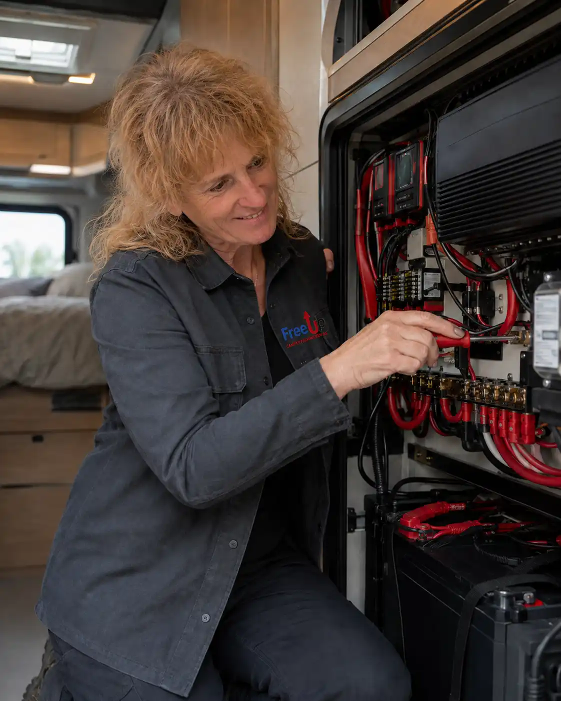 Billie van FreeUp Campertechnieken werkt aan de elektrische installatie van een camper